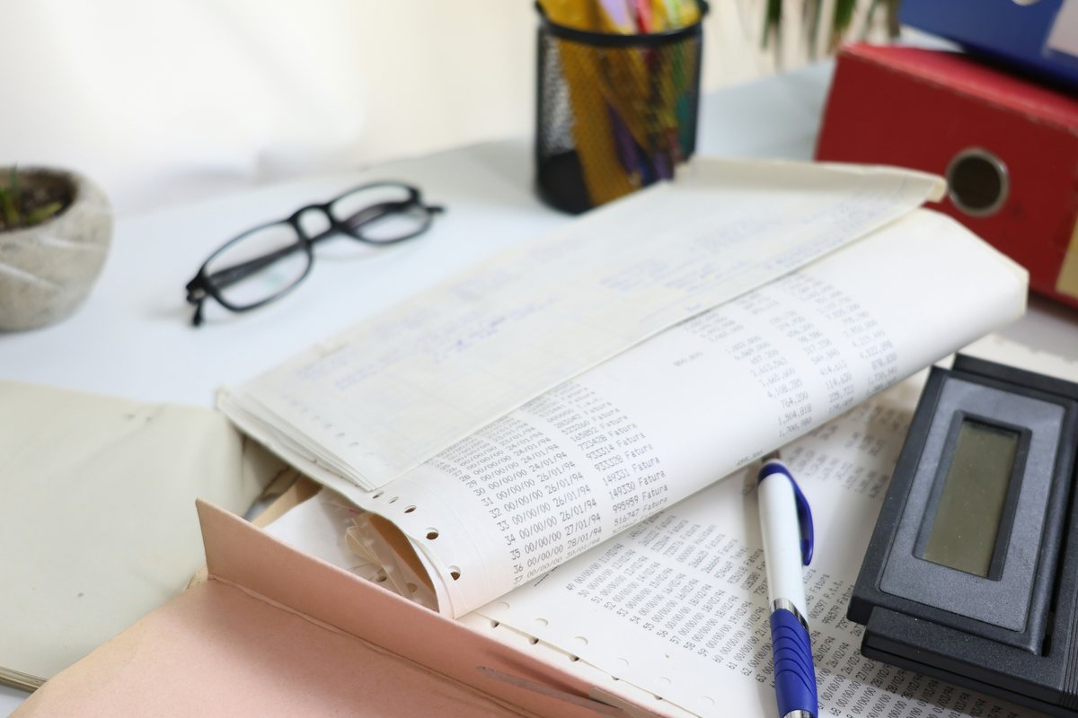 Schreibtisch mit Unterlagen, Brille und Taschenrechner