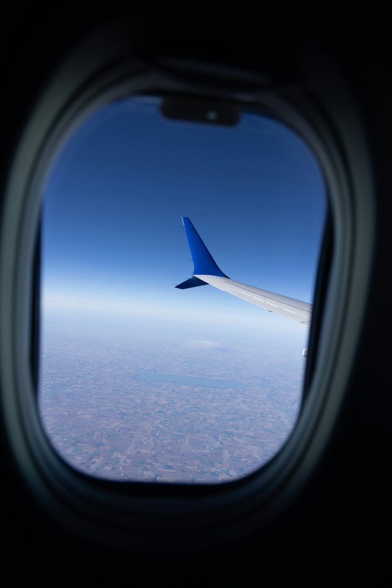 Blick aus dem Flugzeugfenster auf die Tragfläche über den Wolken