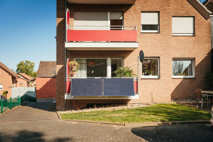 Balkonkraftwerk mit zwei Solarmodulen am Balkongeländer eines Wohnhauses aus Backstein
