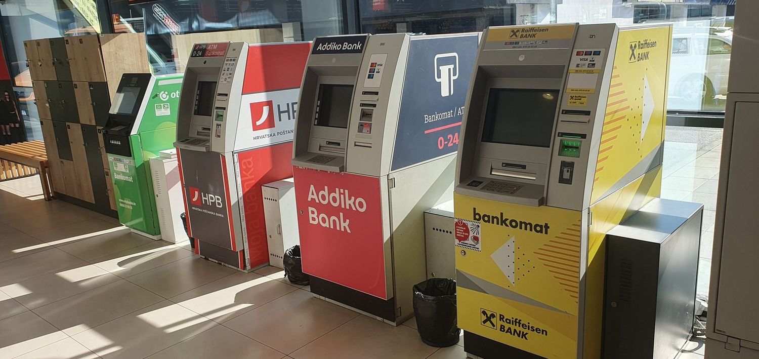 Reihe von Geldautomaten verschiedener Banken in einer hellen Bankhalle