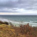 Steilküste und schmaler Strand auf Bornholm an der Ostsee unter bewölktem Himmel