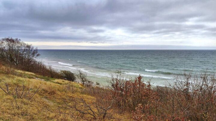 Steilküste und schmaler Strand auf Bornholm an der Ostsee unter bewölktem Himmel