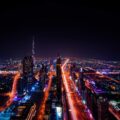 Nachtaufnahme der Dubai-Skyline mit beleuchteten Hochhäusern und Lichtspuren auf der Sheikh Zayed Road