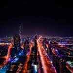 Nachtaufnahme der Dubai-Skyline mit beleuchteten Hochhäusern und Lichtspuren auf der Sheikh Zayed Road