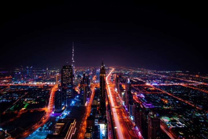 Nachtaufnahme der Dubai-Skyline mit beleuchteten Hochhäusern und Lichtspuren auf der Sheikh Zayed Road