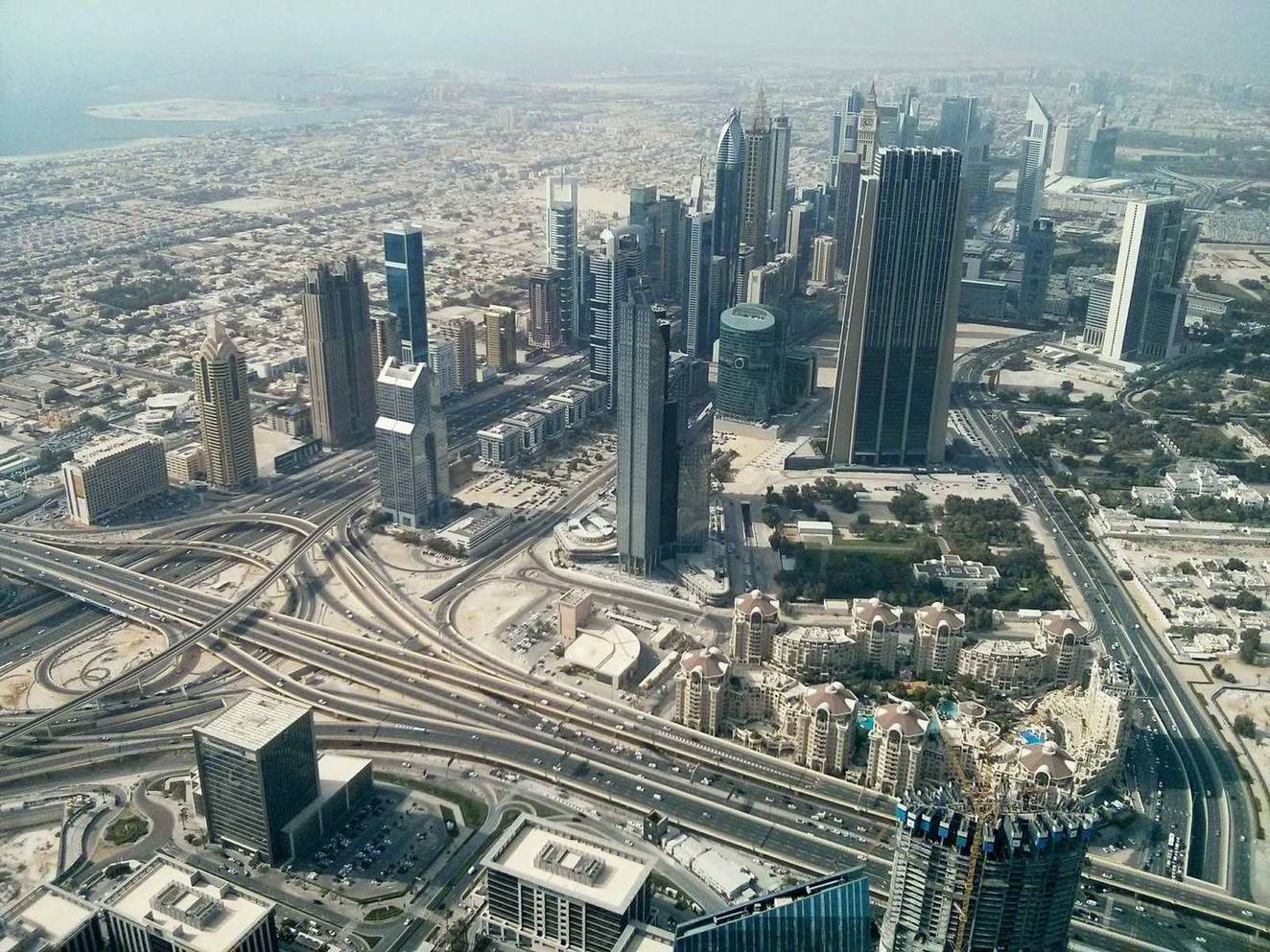 Luftaufnahme der Skyline von Dubai mit Hochhäusern und Autobahnkreuz bei Dunst