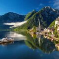 Ort Hallstatt am Hallstätter See mit Kirchturm, Boot und steilen Bergen unter blauem Himmel