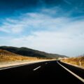 Leere mehrspurige Autobahn durch eine Hügellandschaft unter blauem Himmel