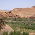 Lehmkasbah Aït Benhaddou in Marokko über einer grünen Oase vor karger Bergkulisse