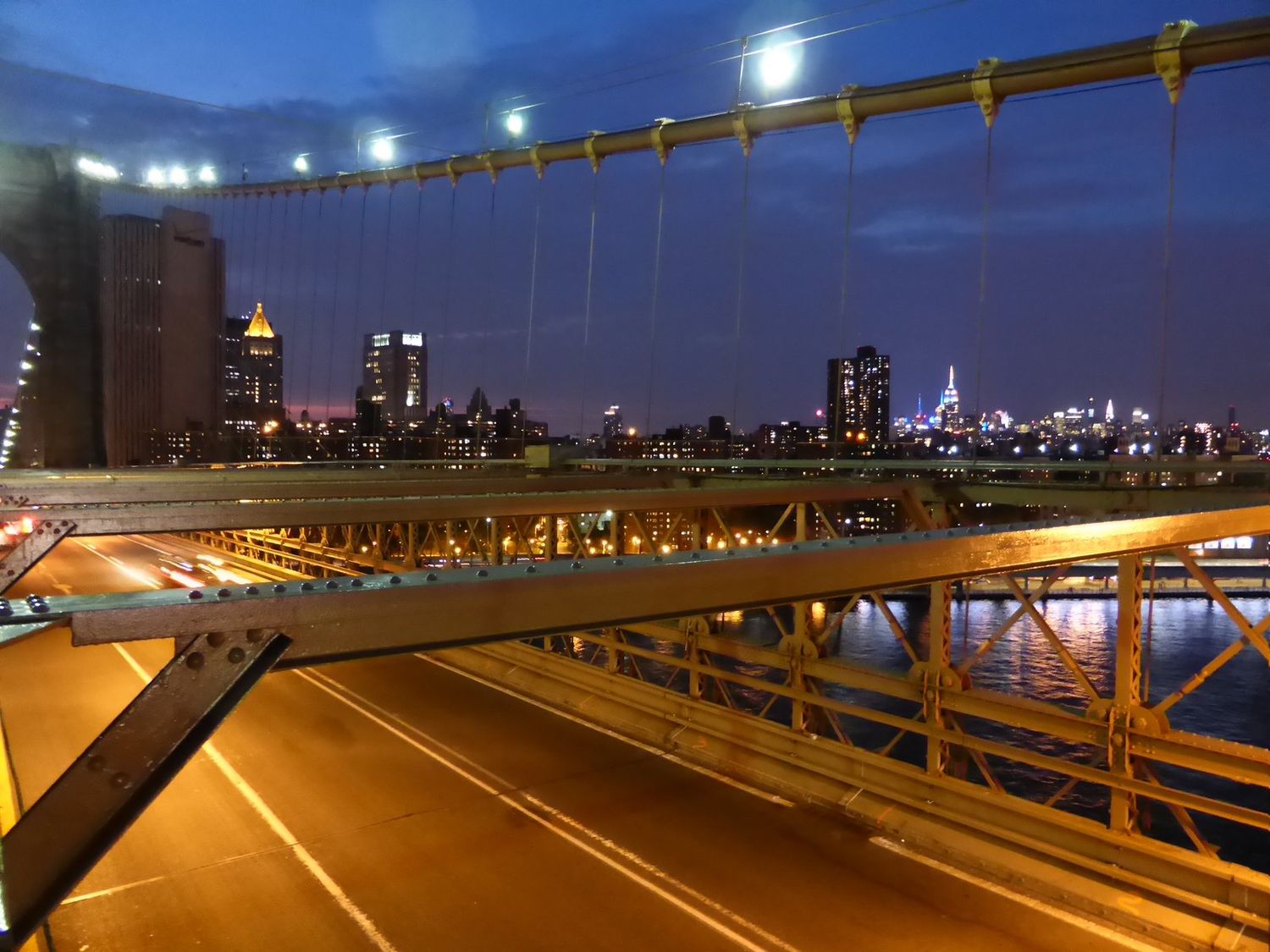Stahlkonstruktion der Brooklyn Bridge bei Nacht mit Blick auf die Manhattan-Skyline
