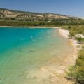 Andalusischer Stausee mit klarem türkisem Wasser, Kiesufer und Olivenhainen an den Hängen